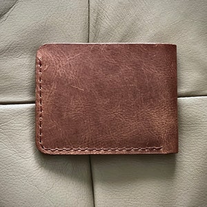 Peut inclure: Un portefeuille en cuir marron avec un bord cousu.