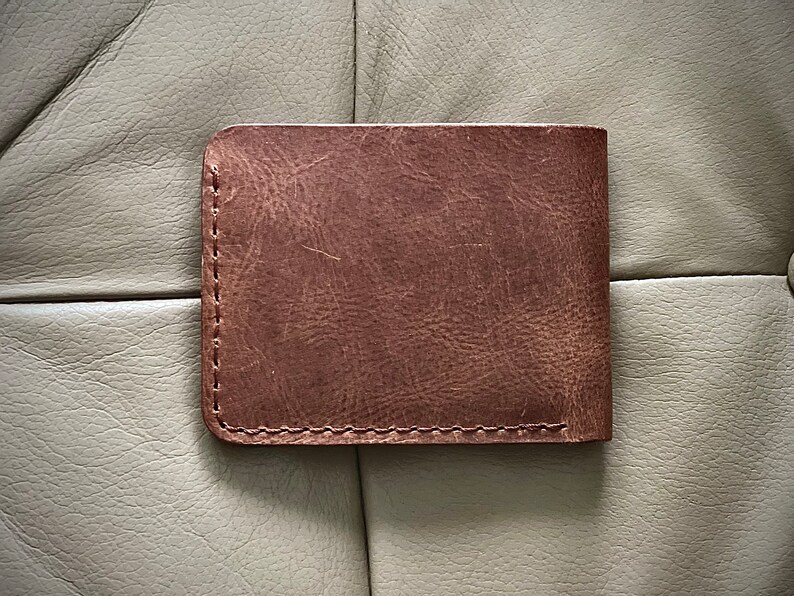 Peut inclure: Un portefeuille en cuir marron avec un bord cousu.
