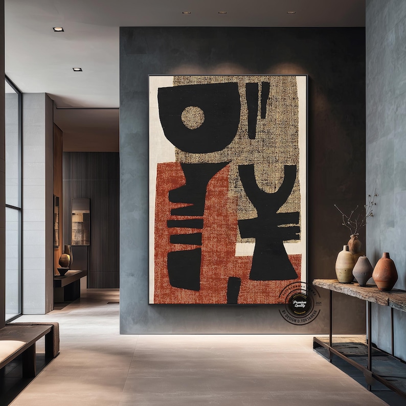 May include: Large abstract canvas art with black, rust, and beige shapes. The artwork features bold geometric forms and textures, creating a modern and minimalist aesthetic. The piece is framed and displayed in a contemporary interior setting.