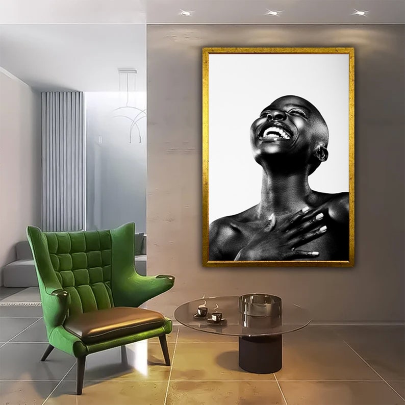 Op de afbeelding: Zwart-witfoto van een lachende vrouw met haar hoofd naar achteren gekanteld. De foto is ingelijst in een gouden lijst en hangt aan een muur.
