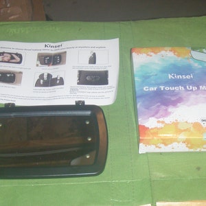 May include: A black car touch-up mirror with 5 LED lights. The mirror is in a clear plastic case with a colorful design and the text "Kinsei Car Touch Up Mirror".