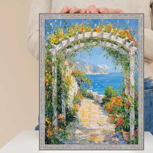 Può includere: Dipinto ad olio incorniciato raffigurante una scena costiera con un pergolato bianco adornato da fiori colorati. Un sentiero in pietra conduce al mare sotto un cielo blu. La cornice è argentata.