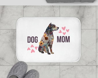 May include: White bath mat with a floral patterned dog illustration and the text "DOG MOM" in pink and black lettering. Pink hearts are scattered around the dog.