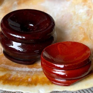 May include: Two wooden display stands, one dark brown and one red, with a smooth, glossy finish. The stands are round and have a raised lip around the top.