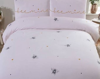 Bee Mine Single. Features delicate bees and hearts on a subtle pink background with the words bee mine on the pillowcase.
