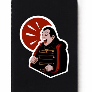 May include: A sticker featuring a cartoon vampire with a red cape and a black and gold striped jacket. The vampire is smiling and has a red speech bubble behind him.