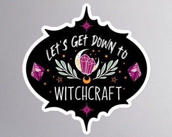 May include: Black and white sticker with the text "Let's Get Down to Witchcraft" in a white font. The sticker features a crescent moon, stars, and crystals in pink and gold.
