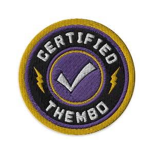 以下が含まれることがあります： 黄色い縁取り、黒い背景、紫色の中心を持つ丸い刺繍パッチ。パッチには、白いチェックマークの周りに白い文字で「CERTIFIED THEMBO」と書かれています。