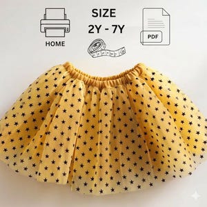 Peut inclure: Une jupe en tulle jaune avec un motif d'étoiles noires et une taille élastique. Au-dessus, le texte indique SIZE 2Y - 7Y, accompagné d'icônes d'une imprimante marquée HOME, d'un mètre ruban et d'un document PDF pour impression à domicile.