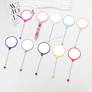 May include: Ten handheld mirrors with different colored handles and round mirrors. The handles are made of metal and the mirrors are attached to the handles with a small ball at the end. The mirrors are all the same size and shape.