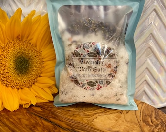May include: A blue resealable pouch filled with white bath salts. The pouch has a label that reads "Cleansing Bath Salts with Sea Salt, Herbs & Essential Oils".