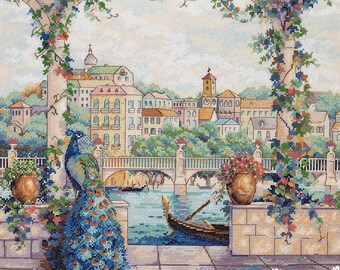 May include: A colorful cross-stitch pattern depicting a peacock standing on a stone patio overlooking a canal with a gondola and a bridge in the background. The scene is framed by lush greenery and flowers.