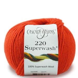 May include: A ball of orange Cascade Yarns 220 Superwash wool. The label reads "100% Superwash Wool". The yarn is a vibrant, solid color, perfect for knitting or crocheting projects. The ball of yarn is round and tightly wound.