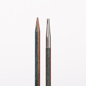 May include: Two knitting needles, one with a wooden shaft and a pointed tip, the other with a metal shaft and a double-pointed tip. Both needles have a blue and brown wood grain pattern.