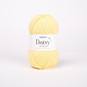 以下が含まれることがあります： 「DROPS Daisy UNI COLOUR 100% extra fine merino wool」とラベル付けされた、薄い黄色の糸のボール
