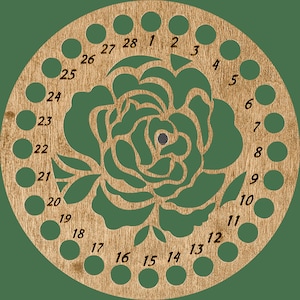 Może przedstawiać: Drewniany motowidło do przędzy z wyciętym laserowo wzorem róży pośrodku. Motowidło ma 28 równomiernie rozmieszczonych otworów wokół obwodu, każdy oznaczony numerem. Drewno ma naturalny, jasnobrązowy kolor, tło jest czarne.
