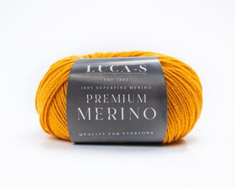 May include: A ball of bright yellow yarn with a black label that reads "LUCA-S EST 1992 100% SUPERFINE MERINO PREMIUM MERINO QUALITY FOR EVERYONE"