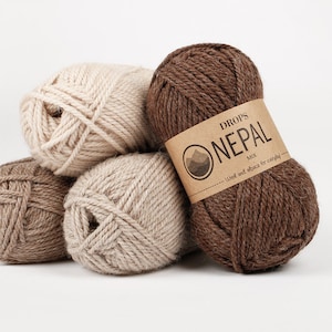 May include: Four balls of yarn in brown and beige colors. The brown yarn ball has a label that reads "DROPS ONEPAL MIX Wool and alpaca for everyday."