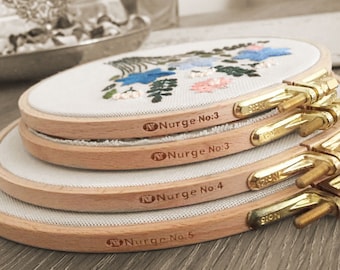 May include: Four wooden embroidery hoops stacked on top of each other. The hoops are labeled with the text "Nurge No. 3", "Nurge No. 3", "Nurge No. 4", and "Nurge No. 5".