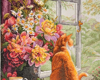 May include: A ginger cat sits by a window looking out at a garden. A vase of colorful flowers sits on a table next to the cat. A teacup and saucer are on the table.