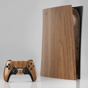 Puede incluir: Una consola de juegos y un mando a juego con acabado de madera. La consola tiene un diseño vertical con paneles de madera. El mando tiene un acabado de madera a juego con botones y detalles en negro.