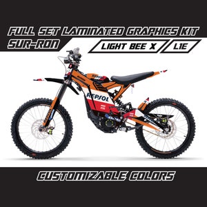 May include: A full set of laminated graphics kit for a Sur-Ron Light Bee X electric motorcycle. The graphics feature a black, white, and orange color scheme with the Repsol logo and branding. The kit is customizable with different colors.