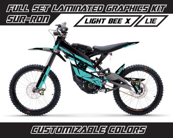 May include: A black and turquoise Sur-Ron Light Bee X electric dirt bike with a custom graphics kit. The graphics feature the brand name "Sur-Ron" and the number "84". The kit is customizable with different colors.