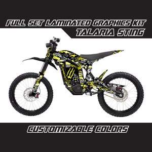 Può includere: Una moto da cross elettrica nera e gialla con un kit grafico personalizzato. Le grafiche presentano una varietà di disegni, tra cui teschi, fiamme e le parole "Talaria Sting".