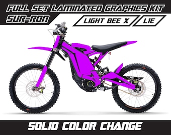 May include: A bright pink Sur-Ron Light Bee X electric dirt bike with black wheels and a black seat. The bike has a full set of laminated graphics kit.