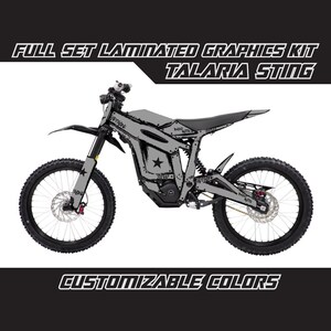 May include: A grey and black electric dirt bike with a custom graphic design. The design features a star, the words "Super" and "Everywhere", and other graffiti-style text. The bike is called "Talaria Sting".