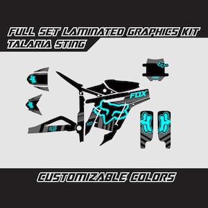 May include: Full set of laminated graphics kit for a motorcycle, featuring a black and gray design with a blue fox logo and the word "FOX". The kit is customizable with different colors.