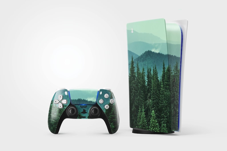 May include: A gaming console and controller set featuring a nature-themed design. The console and controller are adorned with a landscape of green trees and mountains. The controller has white buttons and black accents.