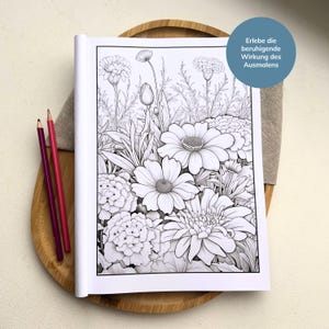 May include: A black and white coloring book page featuring a detailed illustration of a garden with various flowers. The text "Erlebe die beruhigende Wirkung des Ausmalens" is printed in the top right corner.