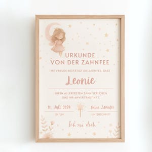 May include: A framed certificate with a fairy illustration and the text "URKUNDE VON DER ZAHNFEE". The certificate is in a light wood frame and features a fairy illustration, stars, and floral accents. The name "Leonie" is prominently displayed.