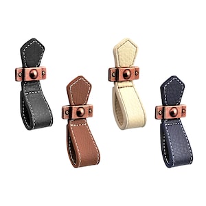 May include: Four leather cabinet pulls with a copper finish. The pulls are in black, white, brown, and blue.