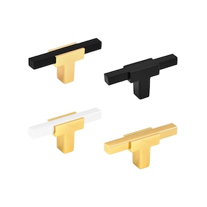 May include: Four cabinet knobs in different finishes: black, white, gold, and black with a gold accent. Each knob has a T-shaped design with a flat top and a square base.