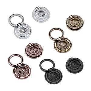 May include: Eight decorative cabinet knobs with a ring pull. The knobs are in various finishes including silver, brass, black, and copper.