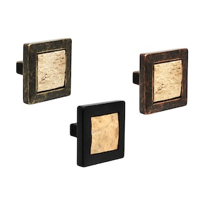May include: Three square cabinet knobs with a wood-like design in the centre. The knobs are in black, bronze, and antique brass finishes.