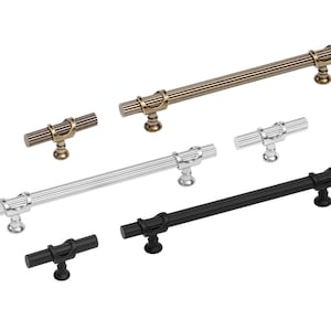 May include: Five different cabinet pulls in various finishes. The pulls are all made of metal and have a fluted design. The finishes include black, silver, and antique brass.