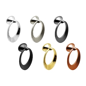 May include: Six different finishes of a ring-style cabinet pull. The pulls are made of metal and have a rounded, oval-shaped ring. The finishes include polished nickel, satin nickel, black, gold, and copper.