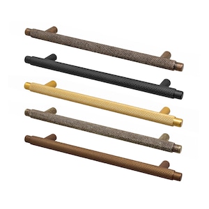 May include: Five cabinet pulls in different finishes: bronze, black, gold, brown, and antique bronze. Each pull is a long, cylindrical shape with a textured surface.