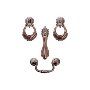 May include: Set of four antique-style cabinet hardware pulls in a copper finish. Two are ring pulls with ornate details and two are cup pulls with a simple design.