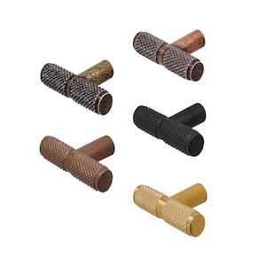 May include: Set of five t-bar cabinet knobs in different finishes: black, copper, brass, bronze, and antique brass. Each knob has a textured, ridged surface.