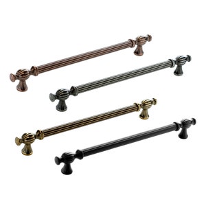 May include: Four cabinet pulls in different finishes: antique brass, oil rubbed bronze, black, and pewter. Each pull has a fluted design and a decorative knob.