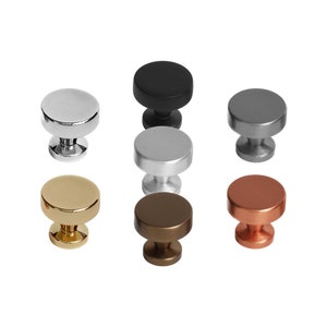 May include: Set of seven cabinet knobs in various finishes, including black, silver, gold, copper, and brushed nickel. Each knob has a round top and a cylindrical base.