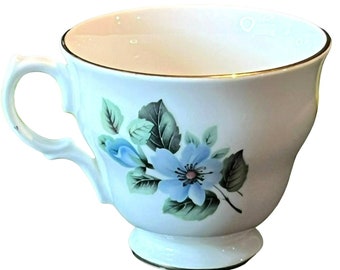 May include: A white teacup with a blue floral design and a gold rim. The cup has a delicate handle and a flared base.
