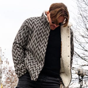 Peut inclure: Une veste à motif gris et noir avec une doublure en sherpa marron. La veste a une fermeture à boutons et un col.