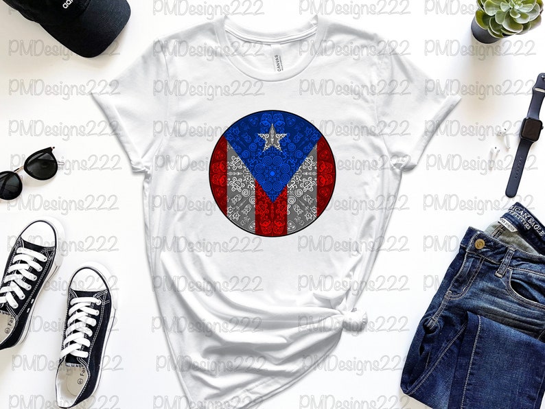 May include: White t-shirt with a circular design of the Puerto Rican flag. The flag is red, white, and blue with a star in the upper left corner. The design is surrounded by a gray and white pattern.