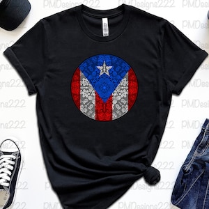 May include: Black t-shirt with a white circle design featuring the Puerto Rican flag. The flag is red, white, and blue with a star in the upper left corner. The circle design is surrounded by a white border.