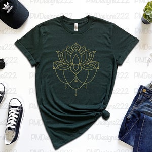 Puede incluir: Camiseta verde oscuro con un dise&ntilde;o de flor de loto dorada. La imagen incluye vaqueros azules, gafas de sol negras, una gorra negra y zapatillas deportivas blancas y negras. Tambi&eacute;n se ven una peque&ntilde;a planta suculenta y un reloj inteligente.